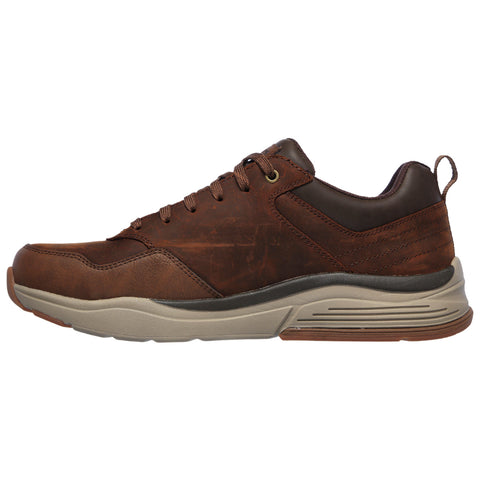 Brown leather sneaker with a thick grey sole is positioned sideways showcasing its curved design and laced detail set against a plain white background.