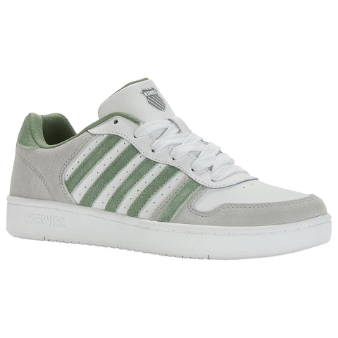 A white and green sneaker sits upright showcasing a smooth leather and suede texture with three green stripes on the side laced with white shoelaces and a logo on the tongue.