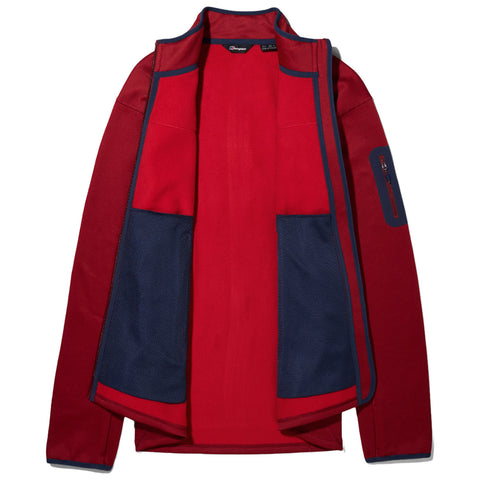 A red jacket with navy blue mesh pockets is displayed flat and open showing its interior design and contrasting colors in a well-lit setting.