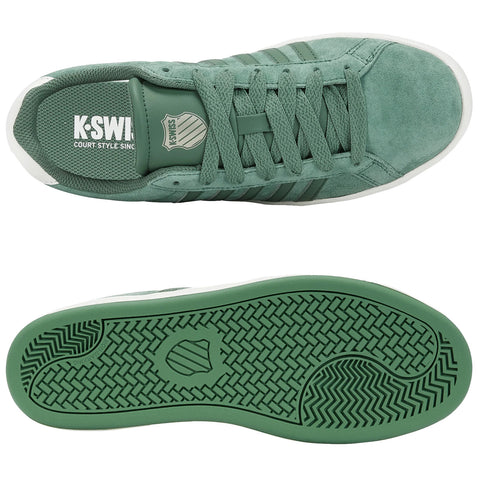 A pair of green athletic shoes is displayed on a white background featuring a textured upper material and a patterned rubber sole showcasing branding and a shield logo.
