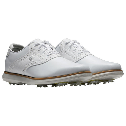 White golf shoes with a sleek design feature decorative perforations and laces positioned centrally. They rest on a light surface with spiked soles, suggesting outdoor use in golfing contexts.