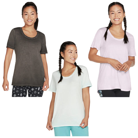 Three women are smiling while wearing various colored t-shirts in a casual display. The shirts are short-sleeved and simple in design, set against a plain white background.