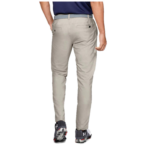 Light-colored pants are worn by a person facing away with a hand on their hip in a casual indoor setting, complemented by dark athletic shoes. A shirt is partially visible.