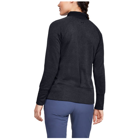 A person wearing a black athletic pullover stands with their back facing the viewer in a light environment showcasing the clothing's texture and style.
