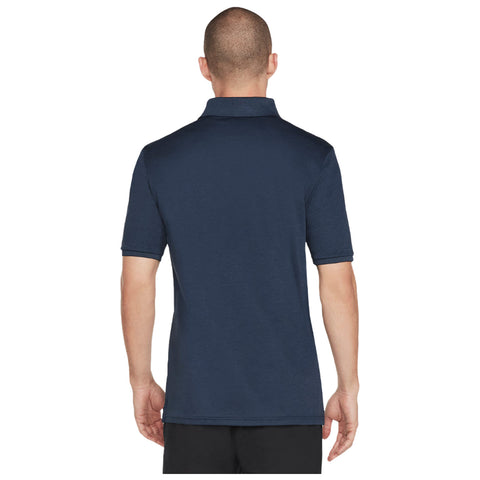 A man is wearing a navy blue polo shirt while facing away. The shirt has short sleeves and a classic collar. He appears in a neutral indoor setting.
