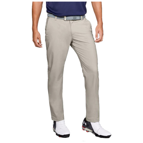 Khaki pants are worn by a person standing with a blue shirt and a belt in a golf attire context, complemented by golf shoes indicating an outdoor sports setting.