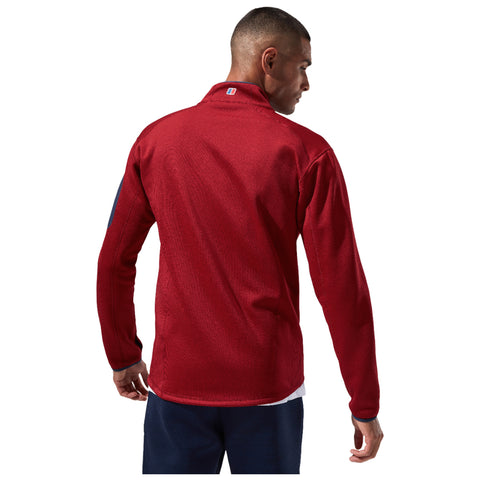 A person stands facing away, wearing a red long-sleeve shirt with a collar. The setting appears neutral, emphasizing the shirt's texture and design details.