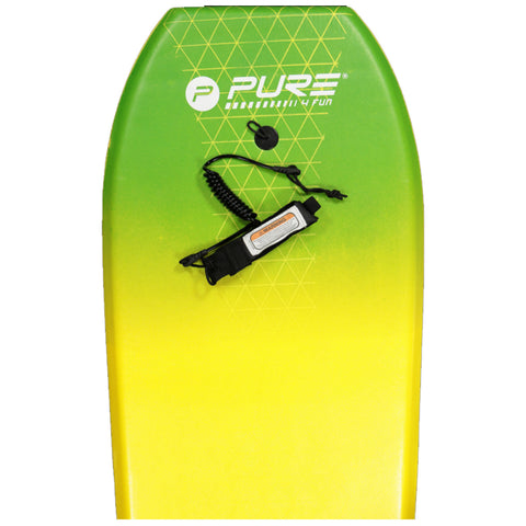 A brightly colored bodyboard in green and yellow with a warning label and a coiled leash attached is resting against a plain background