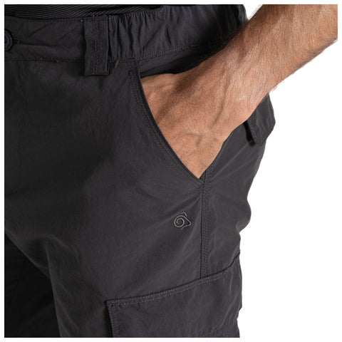 A black pair of cargo shorts is displayed with a hand placed casually in the front pocket showcasing the fabric texture and a small logo near the pocket.