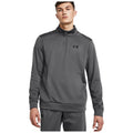 A young man is standing and looking directly at the viewer while wearing a gray zip-up athletic sweatshirt with a black logo on the chest and matching pants.