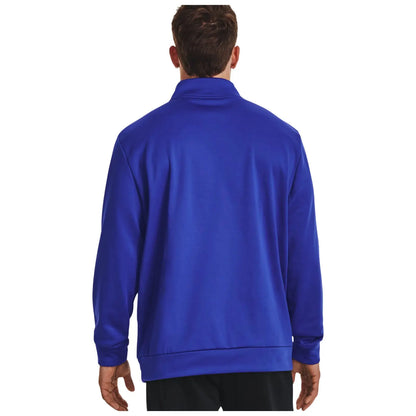 A person wearing a blue long-sleeve jacket stands with their back facing the viewer in a plain white background. The jacket has a high collar and relaxed fit.