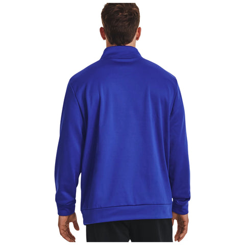 A person wearing a blue long-sleeve jacket stands with their back facing the viewer in a plain white background. The jacket has a high collar and relaxed fit.