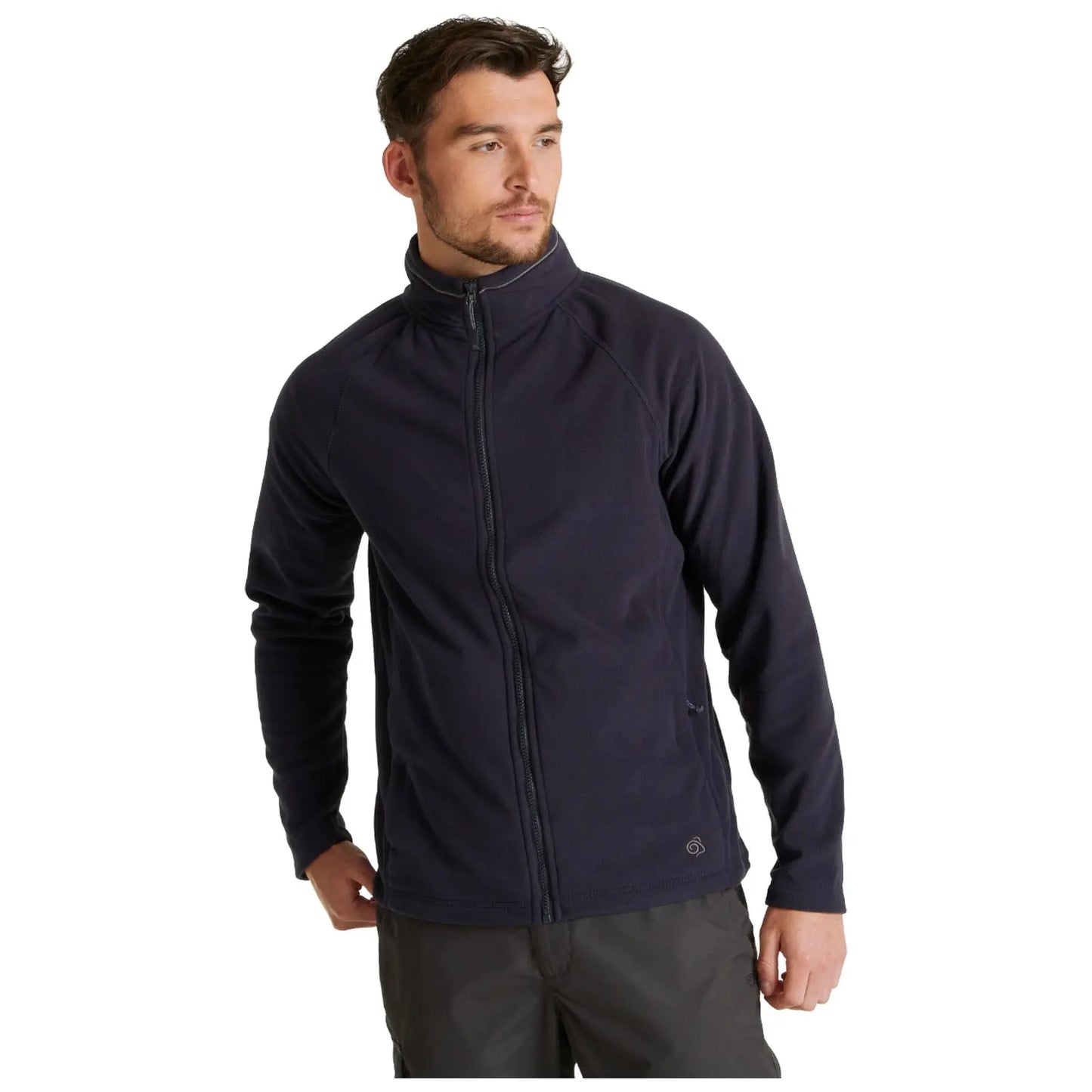 A man is wearing a dark fleece jacket with a zip in a standing pose while looking slightly off to the side in a neutral background.