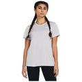 A young woman stands wearing a light gray t-shirt and black leggings with two long braids. She faces forward with a neutral expression against a plain background.