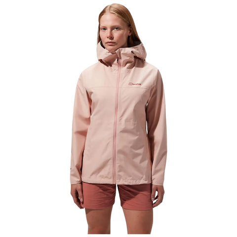 A person wears a light pink waterproof jacket with a hood standing confidently in neutral lighting while wearing coordinating shorts representing an outdoor or active lifestyle.