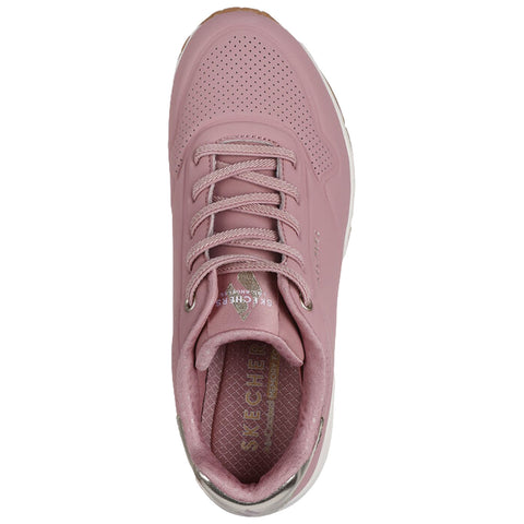 A pink sneaker with a smooth surface and perforated details features a lace-up design. The interior shows a cushioned insole labeled SKECHERS, designed for comfort andstyle.
