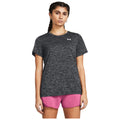 A person is standing, wearing a dark gray t-shirt and pink shorts, with braided hair. The background is plain white, emphasizing the clothing and the individual.