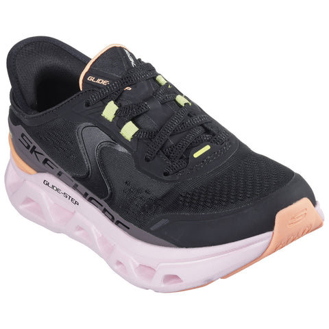 A black athletic shoe with a mesh upper and thick cushioned sole is positioned on a flat surface showcasing its laces and vibrant accents in yellow and pink.