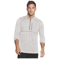 A man stands confidently wearing a light gray zip-up athletic shirt with three-quarter sleeves showcasing a casual yet stylish appearance in a neutral setting.