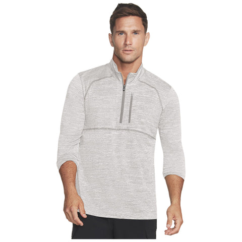 A man stands confidently wearing a light gray zip-up athletic shirt with three-quarter sleeves showcasing a casual yet stylish appearance in a neutral setting.
