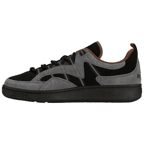 A sneaker features a sleek design with a combination of black and gray suede materials it sits on a dark rubber sole showcasing a casual style suitable for everyday wear