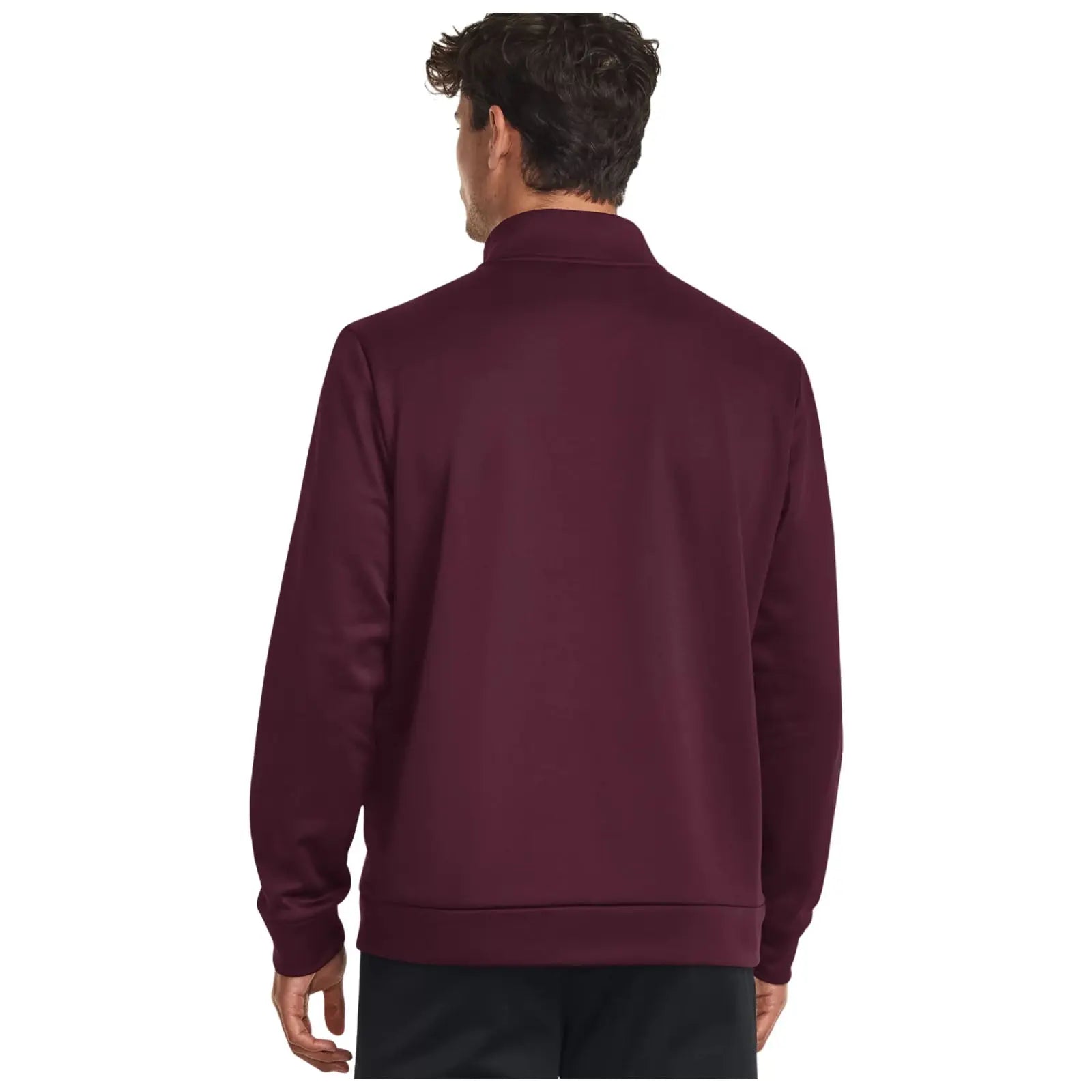 A man stands with his back facing the viewer wearing a dark burgundy pullover with a collar in a plain background emphasizing the clothing.