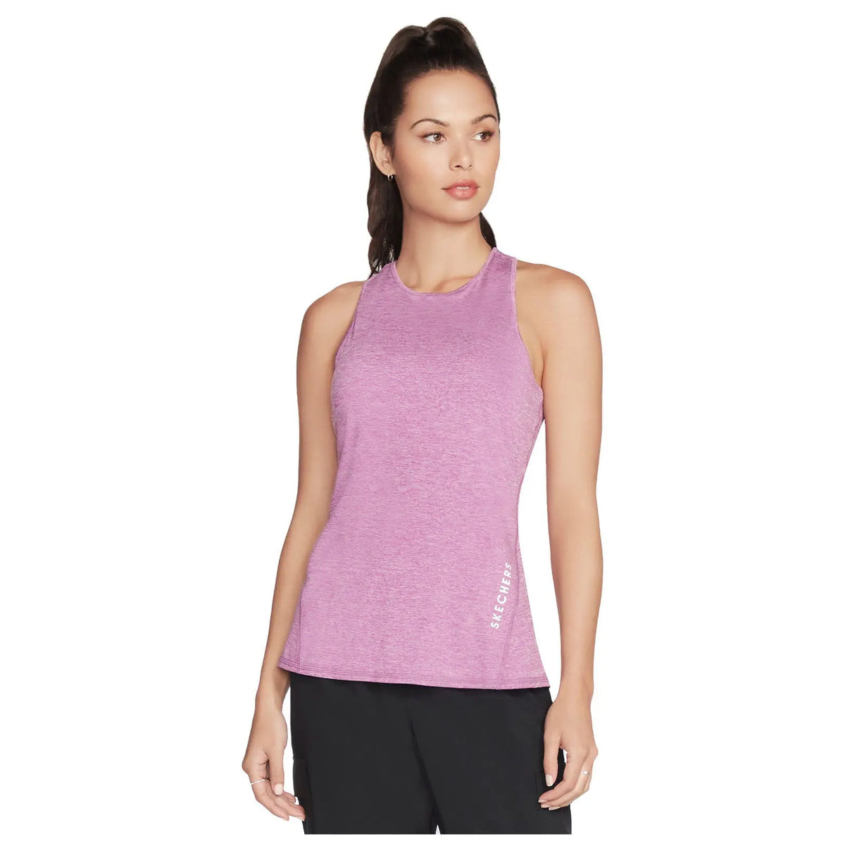 A woman is wearing a sleeveless pink athletic top while posing with a neutral expression in a simple background highlighting her attire. The shirt has the logo SKECHERS on the side.