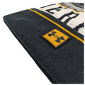 A beanie hat is positioned at an angle displaying its fabric texture and a visible logo emblem the design includes a yellow and black color scheme with a striped pattern.