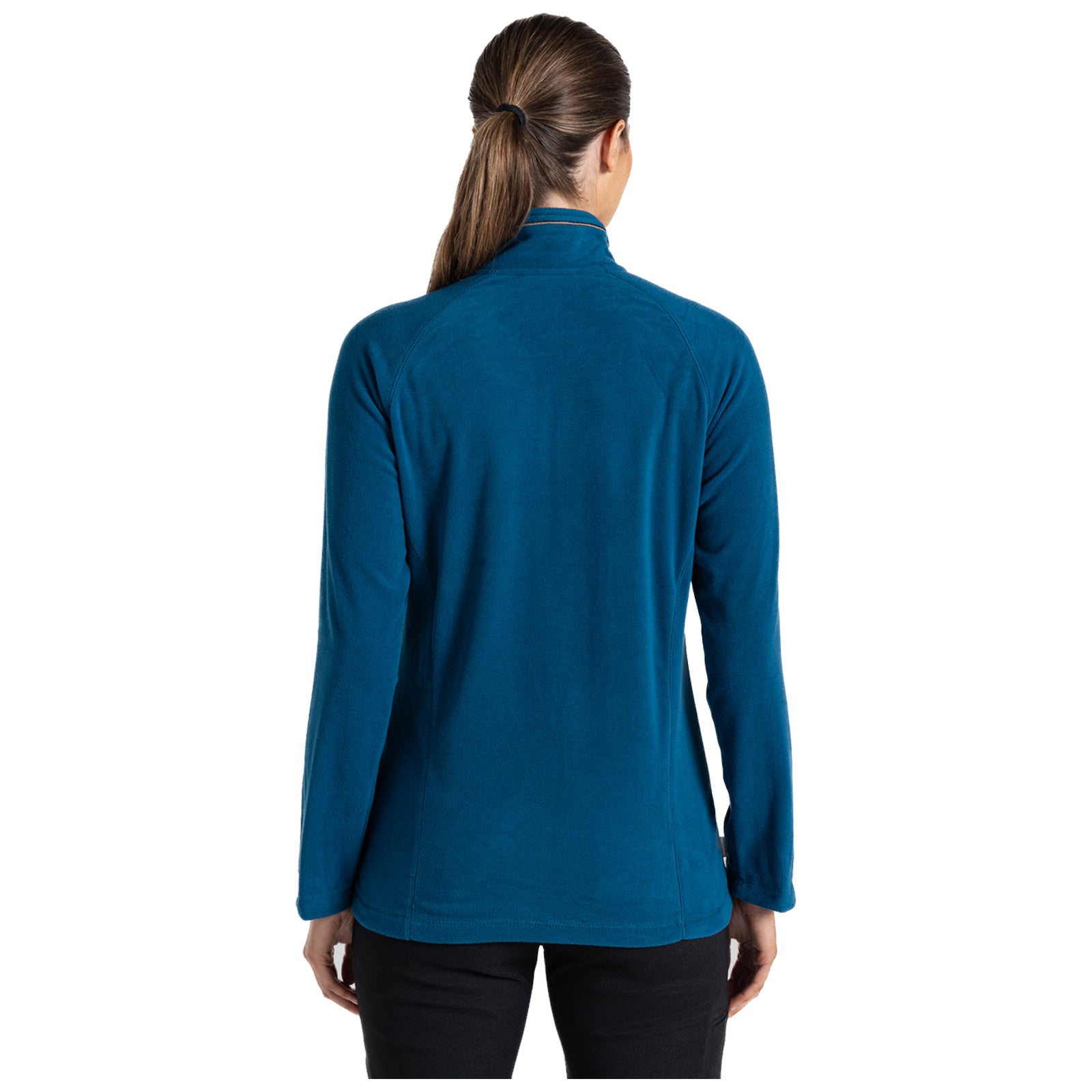 A woman is standing with her back facing the viewer wearing a blue fleece jacket with long sleeves in a plain background, her hair is tied back and she appears to be relaxed.