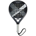 A padel racket features a perforated head with a black and white design and a textured grip handle with a wrist strap while resting on a flat surface.