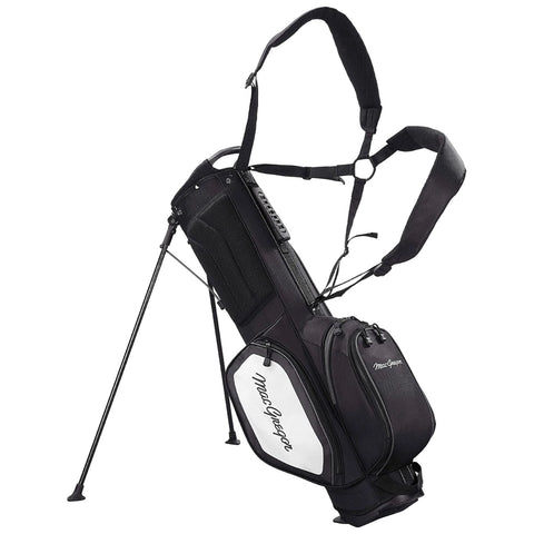A black and white golf bag stands upright with extending legs and shoulder straps designed for carrying. It features multiple zippered pockets and a prominent brand name on the side.
