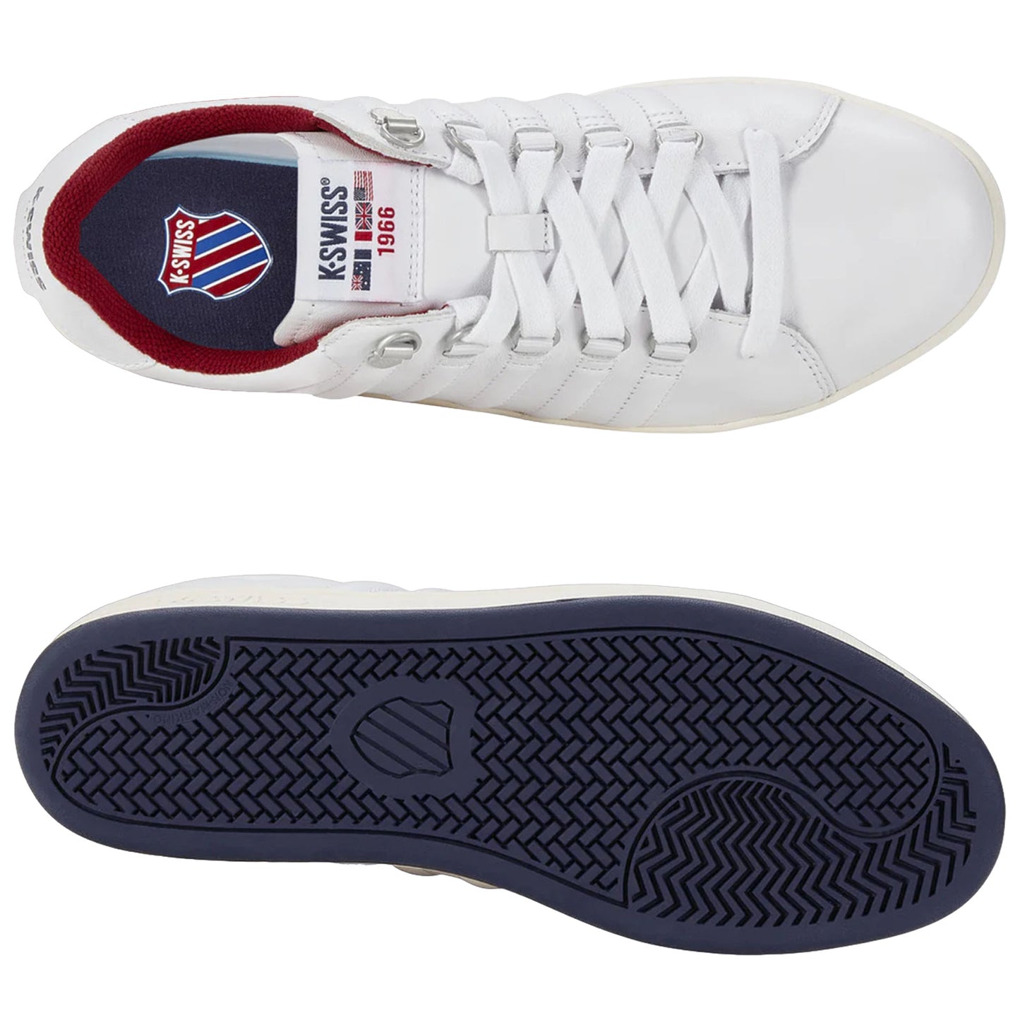 A pair of white athletic shoes is displayed with one shoe inverted to show the navy blue sole while revealing the brand logo and year on the inside of the other shoe.