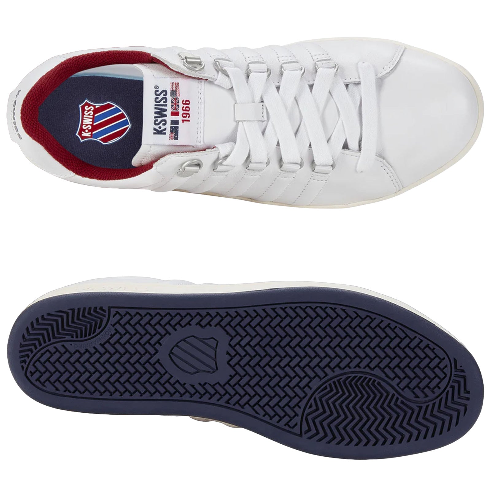 A pair of white athletic shoes is displayed with one shoe inverted to show the navy blue sole while revealing the brand logo and year on the inside of the other shoe.