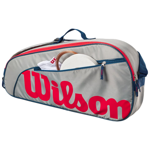 A gray Wilson sports bag unzipped reveals a white disc and a towel inside while prominently displaying the red Wilson logo on the side in a well-lit setting.