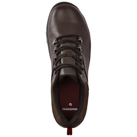 A brown hiking shoe with a textured surface features metal eyelets and black laces. It's placed on a flat surface with a maroon insole displaying the Craghoppers logo inside.