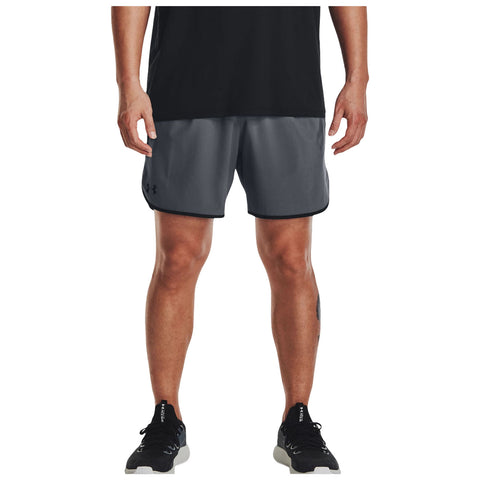 A person is standing wearing black athletic shoes and gray sports shorts with a black waistband. The setting appears to be casual or athletic, focusing on activewear.