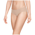 A person is standing and wearing light beige underwear while reaching slightly outward with one hand in a neutral, bright background suggesting a focus on the clothing item.