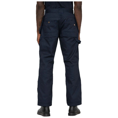 Dark blue work pants are worn by a person facing away showing multiple pockets and loops in an indoor setting with a plain white background. The person is standing still.