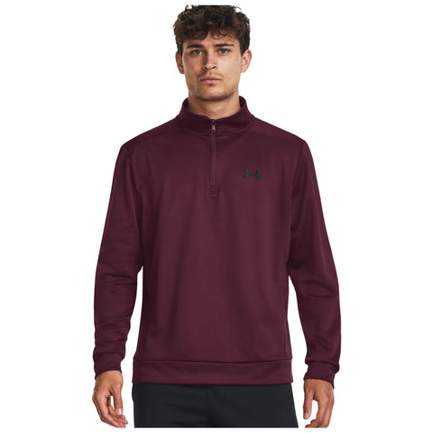 A young man is wearing a maroon quarter-zip pullover with a high collar standing against a plain white background showcasing the garment and its brand logo on the chest.