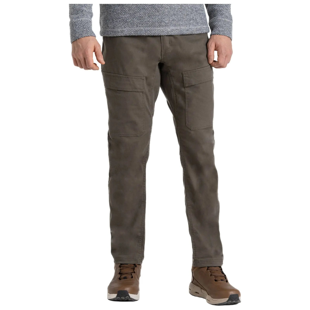 A person stands wearing olive green pants with two large side pockets and brown hiking shoes. They are dressed in a long-sleeve gray patterned shirt, presenting a casual outdoor style.