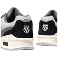 Black and gray athletic shoes are displayed from an angled rear view with a prominent logo on each heel showcasing a stylized shield and brand name K-Swiss on the side.