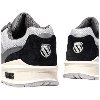 Black and gray athletic shoes are displayed from an angled rear view with a prominent logo on each heel showcasing a stylized shield and brand name K-Swiss on the side.