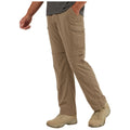 Khaki cargo pants with zip-off legs are worn by a person walking in a casual setting their left hand is in the pocket. The individual is also wearing light-colored shoes.