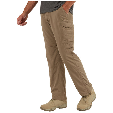 Khaki cargo pants with zip-off legs are worn by a person walking in a casual setting their left hand is in the pocket. The individual is also wearing light-colored shoes.