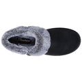 A black slipper with a gray fur lining rests on a flat surface showcasing its cozy design and branding that reads Skechers Memory Foam inside the opening.