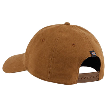 A brown cap rests on a flat surface featuring a curved brim and an adjustable strap at the back with a small logo tag visible on the side.