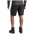 A person is facing away wearing black cargo shorts and hiking boots with gray socks in a casual outdoor setting, suggesting readiness for activities like hiking or exploring.