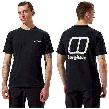 A male model wears a black t-shirt featuring the brand name "berghaus" prominently on the back. He stands facing forward and slightly to the side in a neutral background.