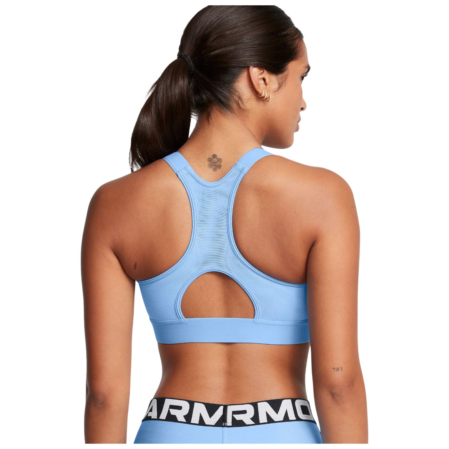 A blue athletic sports bra is being worn by a person facing away from the viewer while wearing black bottoms with a logo The setting suggests an active lifestyle or workout context.