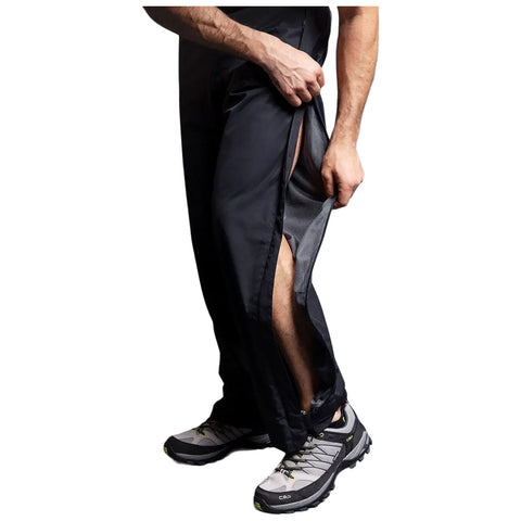 A person is pulling a zippered opening on black pants revealing a mesh lining while wearing gray hiking shoes, likely in an outdoor or athletic context.